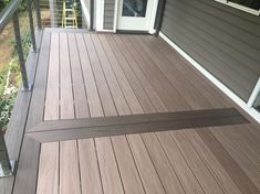 a wooden deck with metal railings next to a door on a house's front porch