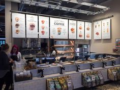 people standing in line at a coffee shop counter with menus on the wall behind them