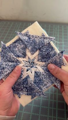 two hands are working on an ornament made out of blue and white fabric