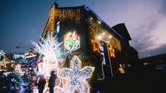 two people standing in front of a building decorated with christmas lights