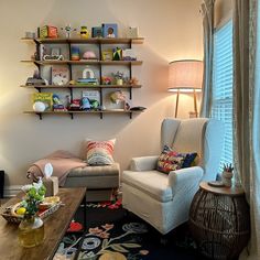 a living room filled with furniture next to a wall mounted book shelf above a window