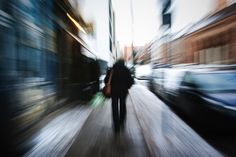 a blurry photo of a person walking down the street in front of some cars