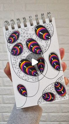 a person holding up a spiral notebook with stickers on it