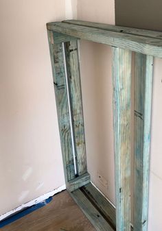 a wooden shelf sitting in the corner of a room next to a wall with paint on it