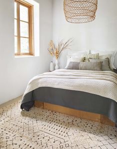 a bed sitting under a window next to a wooden headboard and foot board on top of a rug