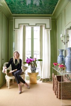 a woman sitting on a chair in a room with green walls and ceiling painted white