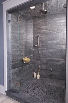 a walk in shower sitting next to a tiled wall and floor covered in gray tile