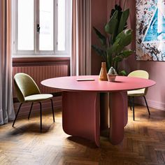 a dining room with pink walls and wooden floors