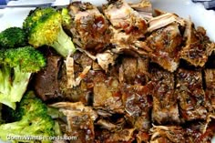 a white plate topped with meat and broccoli on top of a blue table cloth