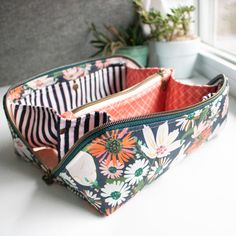 an open zippered pouch sitting on top of a table next to a potted plant