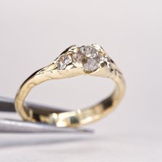 a yellow gold ring with three diamonds on it and a pair of pliers next to it