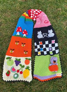 two knitted mittens sitting on top of grass next to each other in different colors