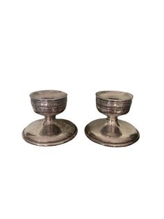 two silver candlesticks sitting on top of each other in front of a white background