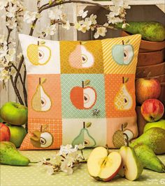 an apple and pear patchwork pillow sitting on a table next to some fruit in baskets