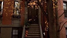 an apartment building with stairs leading up to the front door and pumpkins on the steps