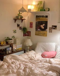 an unmade bed with white sheets and pillows in a small room filled with plants