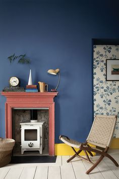 a living room with blue walls and a red fire place in the corner, next to a wicker chair