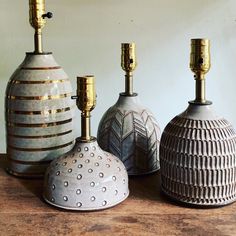 three vases sitting on top of a wooden table next to each other with candles in them