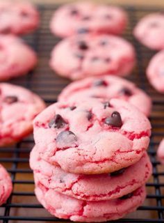 chocolate chip cookies with red and pink icing are arranged on a baking sheet, ready to be eaten