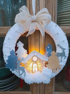 a wreath with a lit candle in the center and snow around it on a door