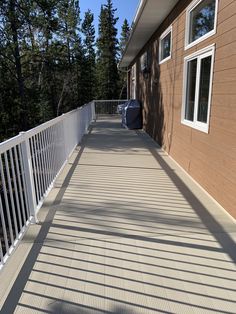 the back porch of a house with white railings and trees in the background on a sunny day