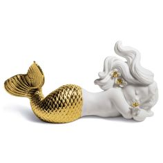 a white and gold mermaid figurine laying on its side