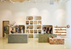 the interior of a clothing store with shelves and vases