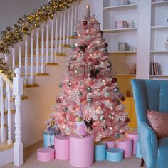 a pink christmas tree sitting in the middle of a living room next to a stair case