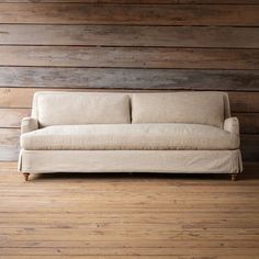 a couch sitting on top of a hard wood floor next to a wooden paneled wall