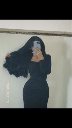 a woman taking a selfie in front of a mirror with her hair blowing back