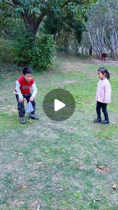 two young children playing with a frisbee in the grass near trees and bushes