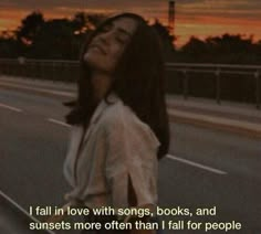 a woman is walking down the street with her head tilted to the side and texting that reads i fall in love with songs, books, and sunsets more than i fall for people