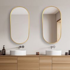 two oval mirrors on the wall above sinks in a bathroom with wood cabinets and white walls