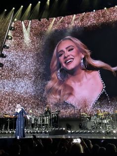 a woman standing on top of a stage in front of a large screen with an image of a woman