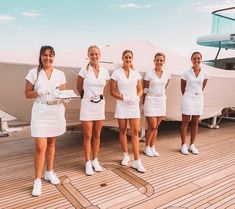 four women in white dresses are standing on a boat