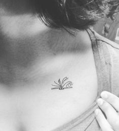 a black and white photo of a woman's chest with a flower tattoo on it