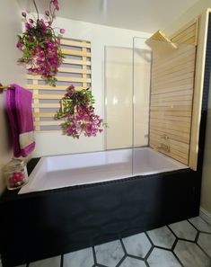 a bath tub with flowers hanging on the wall