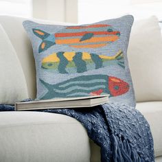 a couch with a book on top of it next to a pillow and throw blanket