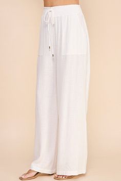 Stay comfortable and stylish in our Linen Wide Leg Pants! Made from soft linen, these pants feature a smock waist and wide leg design for a laid-back yet chic look. With convenient pockets, these pants are both practical and fashionable. Perfect for any casual occasion. Chic Summer Pull-on Style Pants, Chic Cotton Wide Leg Pants With Elastic Waistband, Chic Wide Leg Cotton Pants With Elastic Waistband, Chic Linen Wide Leg Pants With Pull-on Style, Relaxed Fit Wide Leg Pants For Vacation, White Relaxed Wide Leg Pants With Elastic Waistband, Wide Leg Harem Pants With Pockets For Beach, Wide Leg Harem Pants With Pockets For Vacation, White Linen Wide Leg Pants With Elastic Waistband