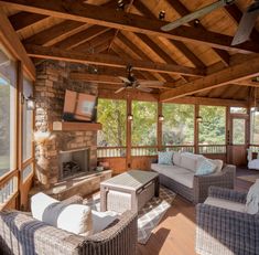 a covered porch with wicker furniture and ceiling fans