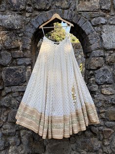 This stunning ivory small butti georgette lehenga is embellished with heavy gota, sequin, pearl and zari work border. It is paired with a mirror and pearl embroidered bustier.   The outfit is completed with an ivory net dupatta. Off White Traditional Wear With Mirror Work For Navratri, Off-white Navratri Traditional Wear With Mirror Work, Navratri Traditional Wear With Mirror Work In Off White, White Kundan Lehenga With Cutdana, Cream Bollywood Dress With Gota Work, Bollywood Style Cream Dress With Gota Work, Bollywood Cream Dress With Gota Work, Anarkali Cream Lehenga With Gota Work, Designer Gold Sharara With Pearl Embroidery