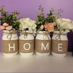 four mason jars with flowers and the word home painted on them