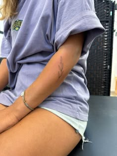 a woman sitting on top of a table with her legs crossed and tattoos on her arm