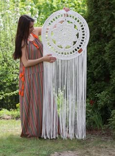 a woman is holding a white crochet dream catcher