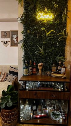 a shelf with liquor bottles and glasses on it in front of a green wall that says cheers