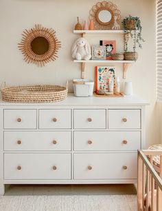 a baby's room with white dressers and shelves