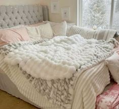 a bed with white blankets and pink pillows