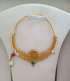 a gold necklace with various colored stones and beads hanging from it's side on a white mannequin