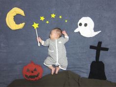 a baby sitting on top of a bed next to halloween decorations