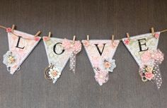 a love banner hanging from a clothes line with flowers and laces on the clothesline